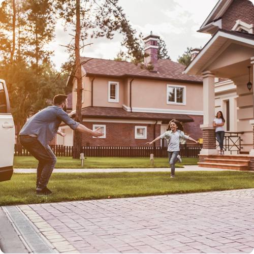 Young girl running across lawn into father's arms