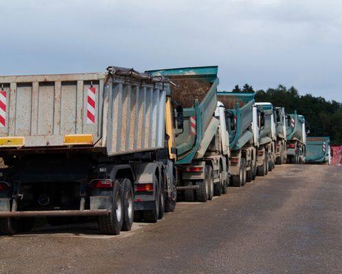 a group of dump trucks with Insurance traveling to a site in Salisbury, NC